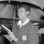 Wilma Rudolph holding an umbrella while wearing a USA Olympic blazer.